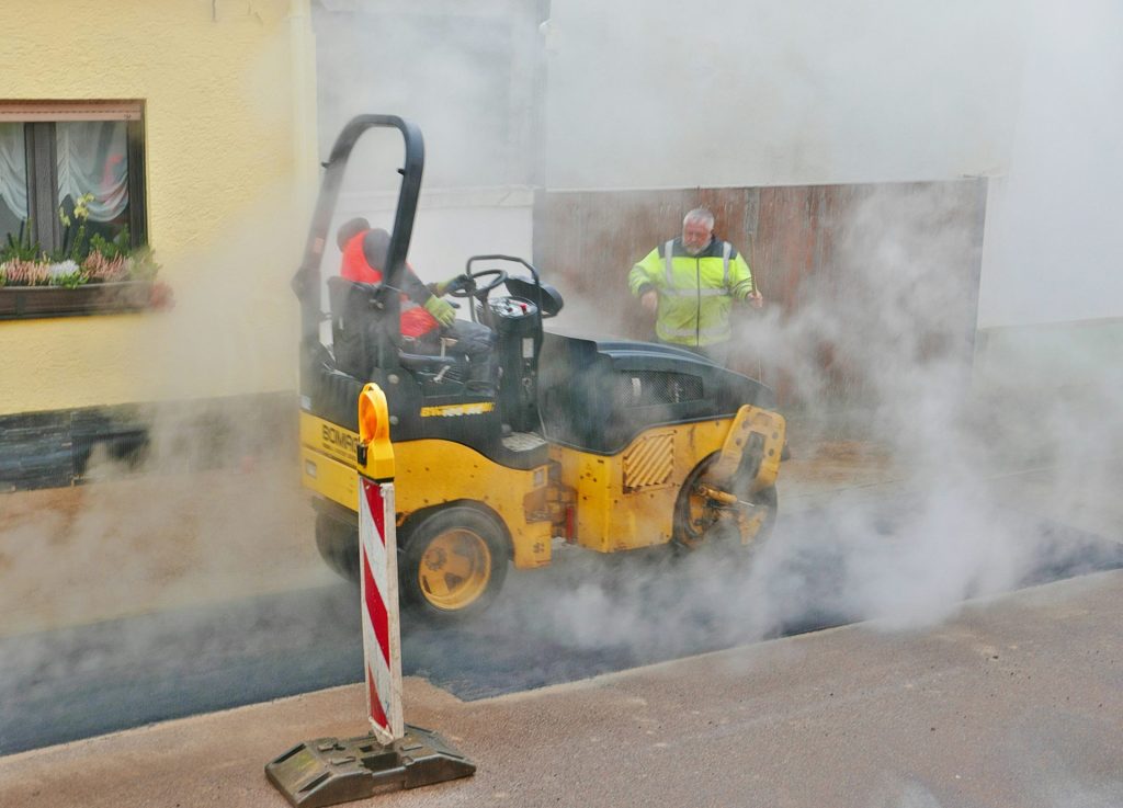 A street sweeper on the side of a road with smoke coming out of it